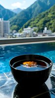 Black ceramic bowl with traditional miso soup served poolside against mountain landscape backdrop, reflecting luxury resort dining experience.