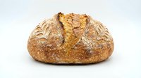 Freshly baked artisan sourdough bread loaf with golden crust and rustic texture isolated on white background for bakery and food design projects.