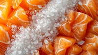 Fresh raw salmon pieces on crushed ice, close up view showing bright orange color and tender texture of premium fish fillet for sushi or cooking.