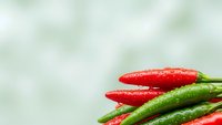 Fresh red and green chili peppers with water droplets on soft blurred background for culinary cooking spice ingredient food photography design.