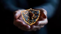 Glowing shield with keyhole symbol held in cupped hands against dark background, representing digital security and data protection concepts for business technology.