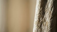 Elegant beige curtain with textured fabric pattern hanging in soft natural light creating warm home interior atmosphere for modern living spaces.