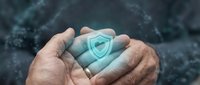 Hands holding glowing shield symbol representing cybersecurity, data protection, and digital safety for technology and business concepts.