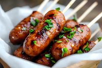 Grilled bratwurst sausages with fresh herbs in white bowl, ready to serve. Delicious barbecue meat for outdoor cooking and summer dining occasions.