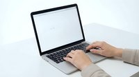Professional businesswoman typing on modern laptop computer with blank white screen for mockup presentations and digital workspace applications.