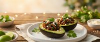 Halved avocados topped with seasoned ground meat, fresh cilantro, and lime on white plate for food styling, recipe development, and culinary content.