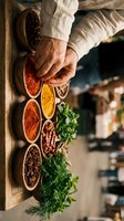 Chef hands selecting aromatic spices from wooden bowls filled with colorful seasonings and fresh herbs for culinary preparation in rustic kitchen.