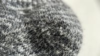 Close-up of gray knitted wool fabric texture with intricate stitch pattern, soft natural fibers, cozy winter textile background.