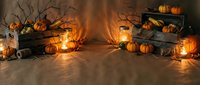 Cozy autumn harvest scene with orange pumpkins, wooden crates, bare branches and warm glowing lanterns creating festive fall atmosphere for seasonal decor.