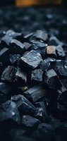Close-up macro shot of black coal pieces showing rough texture and natural patterns. Dark moody background highlights industrial raw material used in energy production.