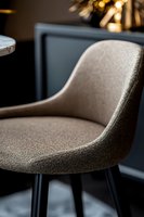 Modern gray upholstered dining chair with curved backrest and black metal legs captured in soft ambient lighting against dark background, luxury interior detail.