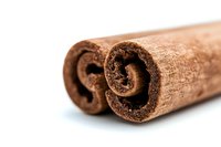 Fresh cinnamon sticks close up on white background showing natural texture and spiral pattern, aromatic spice macro photography for culinary design.