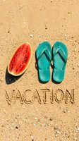 Watermelon slice and teal flip flops on sandy beach with vacation text written in sand, summer holiday concept.