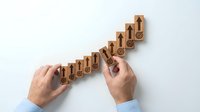 Businessman hands arranging wooden blocks with target icons in ascending steps, representing goal achievement and business growth strategy concept.