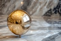Golden reflective sphere balloon on marble surface with dramatic lighting and bokeh effects for luxury event decoration.