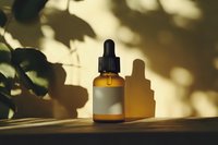 Amber glass dropper bottle with blank label casting shadows on wooden surface in natural sunlight through leaves, creating organic patterns. Wellness concept.