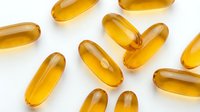 Vitamin supplement capsules in golden yellow tones arranged on white background, suitable for health, wellness, and pharmaceutical marketing materials.
