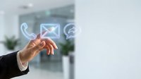 Business professional hand reaching toward floating digital communication icons including phone, email and chat symbols in modern office environment.