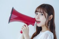 Excited young woman with long dark hair and bangs holding a red megaphone to her mouth against a white background, expressing announcement and communication for marketing and promotional campaigns.