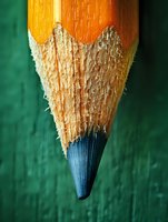 Extreme macro photography of sharpened wooden pencil tip showing detailed texture of wood fibers and blue paint against green background. Creative education concept.