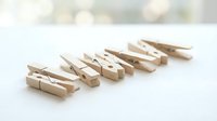 Wooden clothespins arranged in row on white surface for laundry organization and household tasks.