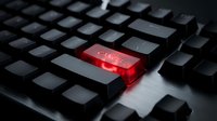 Black computer keyboard with glowing red enter key showing cyber text, representing cybersecurity threats, hacking attacks, and digital crime concepts.