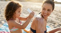Young Caucasian mother and daughter applying sunscreen lotion on beach during summer vacation, sun protection skincare routine for family outdoor activities.