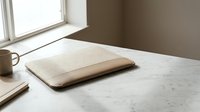 Minimalist workspace with closed laptop on marble desk near window. Clean modern office setup with natural lighting for productivity and remote work concepts.