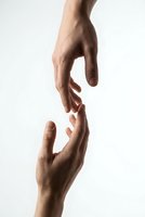 Two hands reaching toward each other in helping gesture on white background symbolizing support, connection, teamwork and human assistance concept.