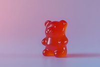Red gummy bear candy standing on pastel purple pink gradient background, sweet gelatin treat with translucent texture, fun confectionery concept.