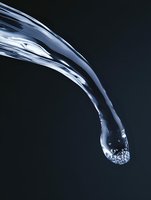 Dynamic stream of pure water with air bubbles forming a curved arc against dark background, capturing liquid motion and transparency in dramatic lighting.