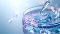 Water drop falling from pipette into glass container with blue liquid, creating ripple effect against blurred bokeh background. Scientific research concept.