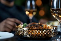 Grilled steak with caramelized crust served on elegant golden tray with wine glass in luxurious restaurant setting, romantic dinner atmosphere with bokeh lights.