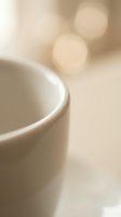 White ceramic coffee cup with soft bokeh lights creating warm cozy atmosphere for morning beverage and relaxation moments.