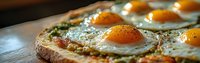 Sunny side up eggs on crusty toasted bread with herbs and spices, extreme close up panoramic view showing runny yolks and crispy edges on wooden surface.
