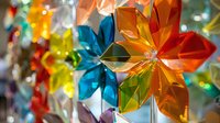 Vibrant origami flowers in orange, blue, yellow and red create a festive hanging decoration with translucent paper catching light, adding depth and sparkle to interior design.