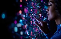 Young Asian woman touching digital data visualization with glowing pink and blue lights, side profile against dark background showing futuristic technology interface.