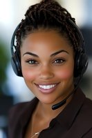 Young African American female customer service representative wearing headset and professional attire smiles warmly at camera, representing positive workplace communication.