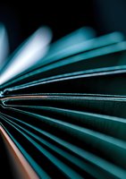 Abstract macro shot of book pages fanned out creating dynamic lines and curves in turquoise and dark tones, dramatic lighting highlights paper texture and shadows.