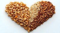 Heart shape made from raw wheat grains and oat flakes on white background, healthy eating concept. Natural organic cereals arranged in love symbol.