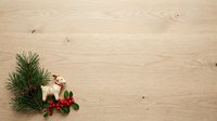 Festive llama figurine with evergreen branches and red berries arranged on light wood surface, perfect for holiday decorations and seasonal design projects.