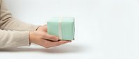 Female hands holding mint green gift box with white ribbon on clean white background for holiday celebrations and special occasions.