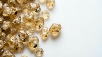 Sparkling golden citrine gemstones scattered on white background for jewelry design and luxury accessories projects.