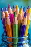 Colorful wooden pencils with sharp tips arranged in glass jar against blurred background for creative art projects and educational supplies.