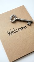 Vintage metal key resting on a kraft paper card with Welcome text, symbolizing new home, hospitality, and real estate concepts.