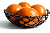 Fresh ripe oranges in decorative black wire mesh bowl against white background, dramatic lighting emphasizes fruit texture and vibrant color. Minimalist food styling.