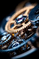 Macro close-up of interlocking metallic gears and cogs with reflective surfaces, showcasing mechanical precision and industrial engineering design against dark background.