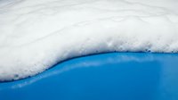 White foam bubbles meeting bright blue water creating natural contrast for spa wellness and relaxation themed designs.