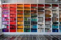 Colorful rainbow bookshelf with books arranged by hue from red to purple, creating vibrant spectrum display in modern library interior.