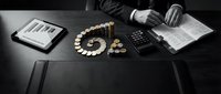 Business professional analyzing financial data with tablet, calculator, coins and documents on dark desk for investment planning and budget management.